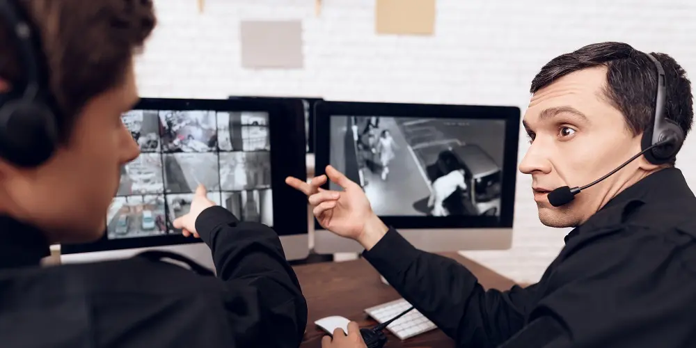 dois homens apontando para tela do computador em uma central de segurança patrimonial.