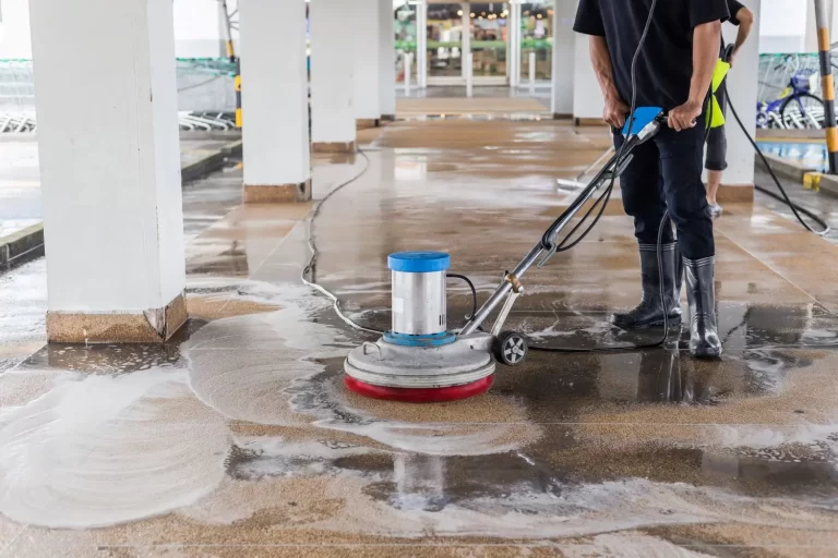 Imagem de homem de preto limpando um piso externo com um equipamento ilustrando o serviço de facilities.