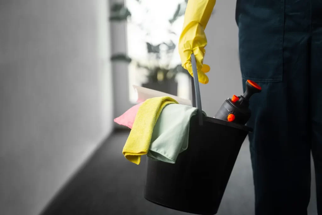 Profissional com produtos de limpeza enquanto faz serviço de limpeza corporativa