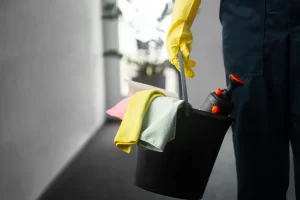 Profissional com produtos de limpeza enquanto faz serviço de limpeza corporativa